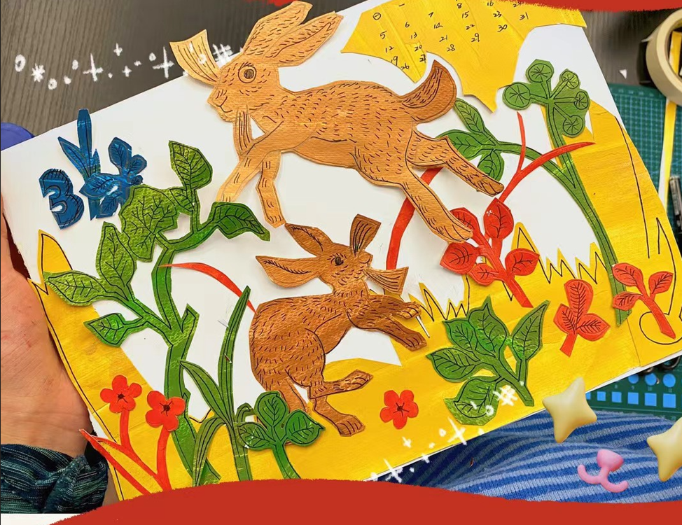 剪纸拼贴创作课学生作品：两只在彩色植物剪纸中奔跑的棕色兔子。